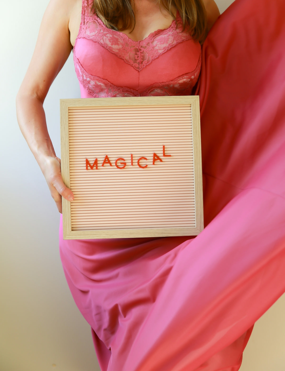 Woman in pink dress holds a sign saying magical.