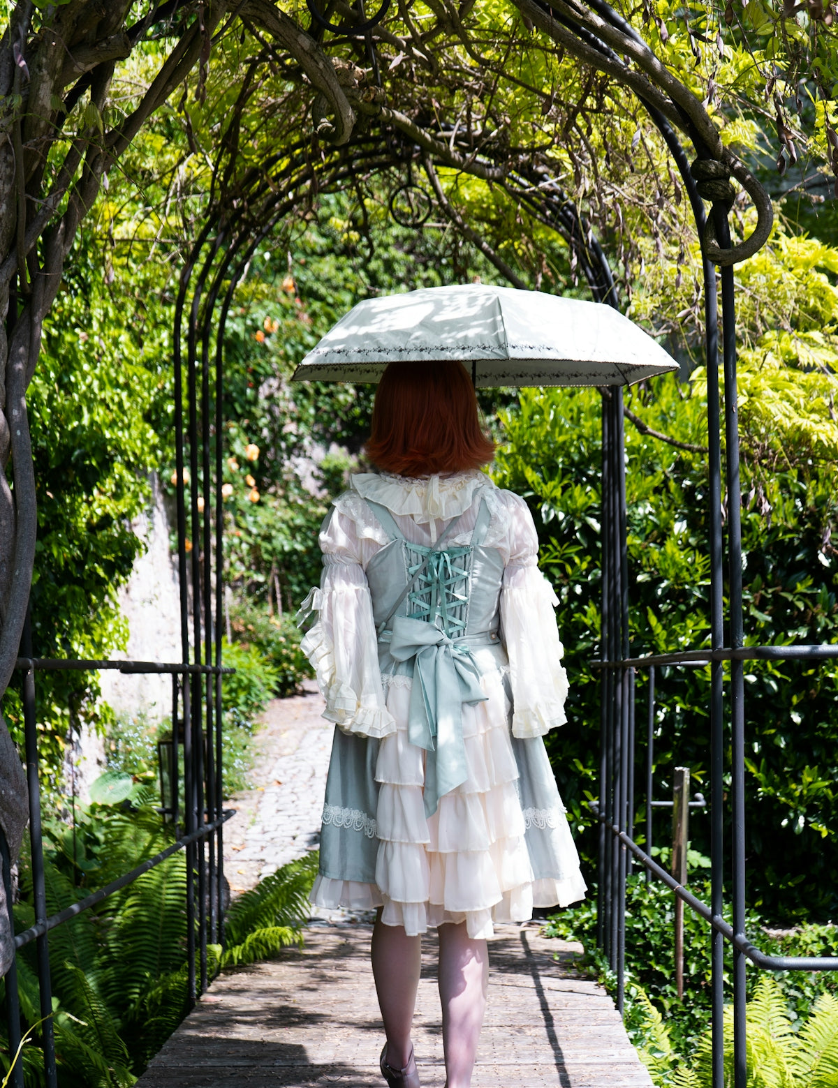 woman in white dress standing on black metal fence
