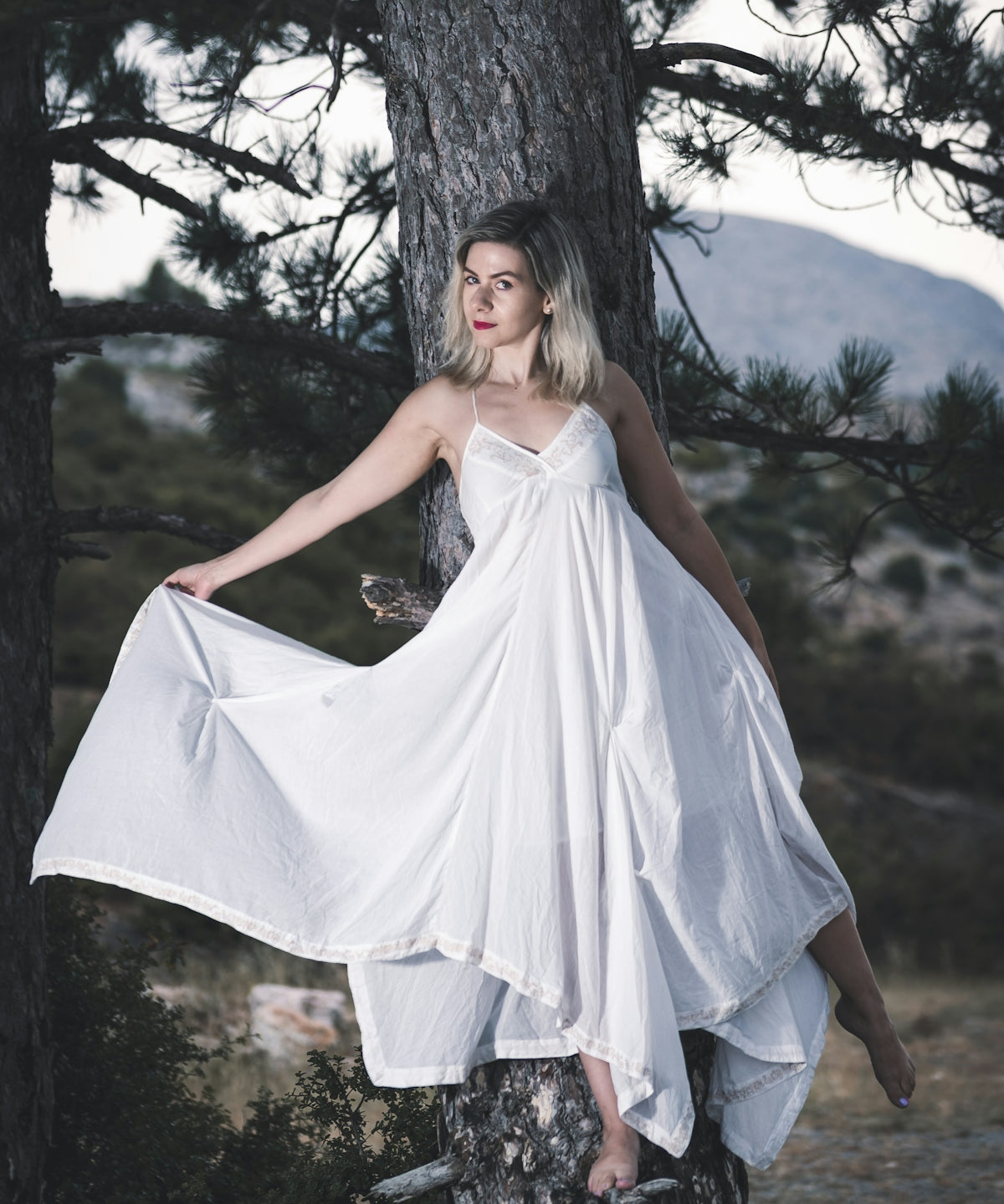 woman in white sleeveless dress standing on brown tree