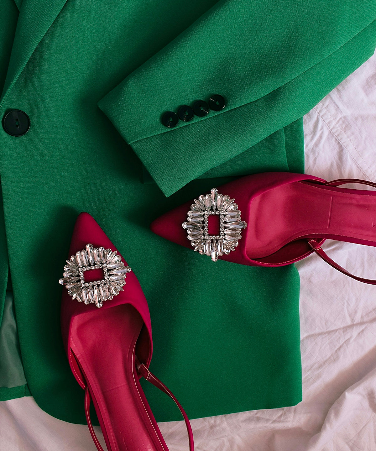 a pair of red high heels sitting on top of a green jacket