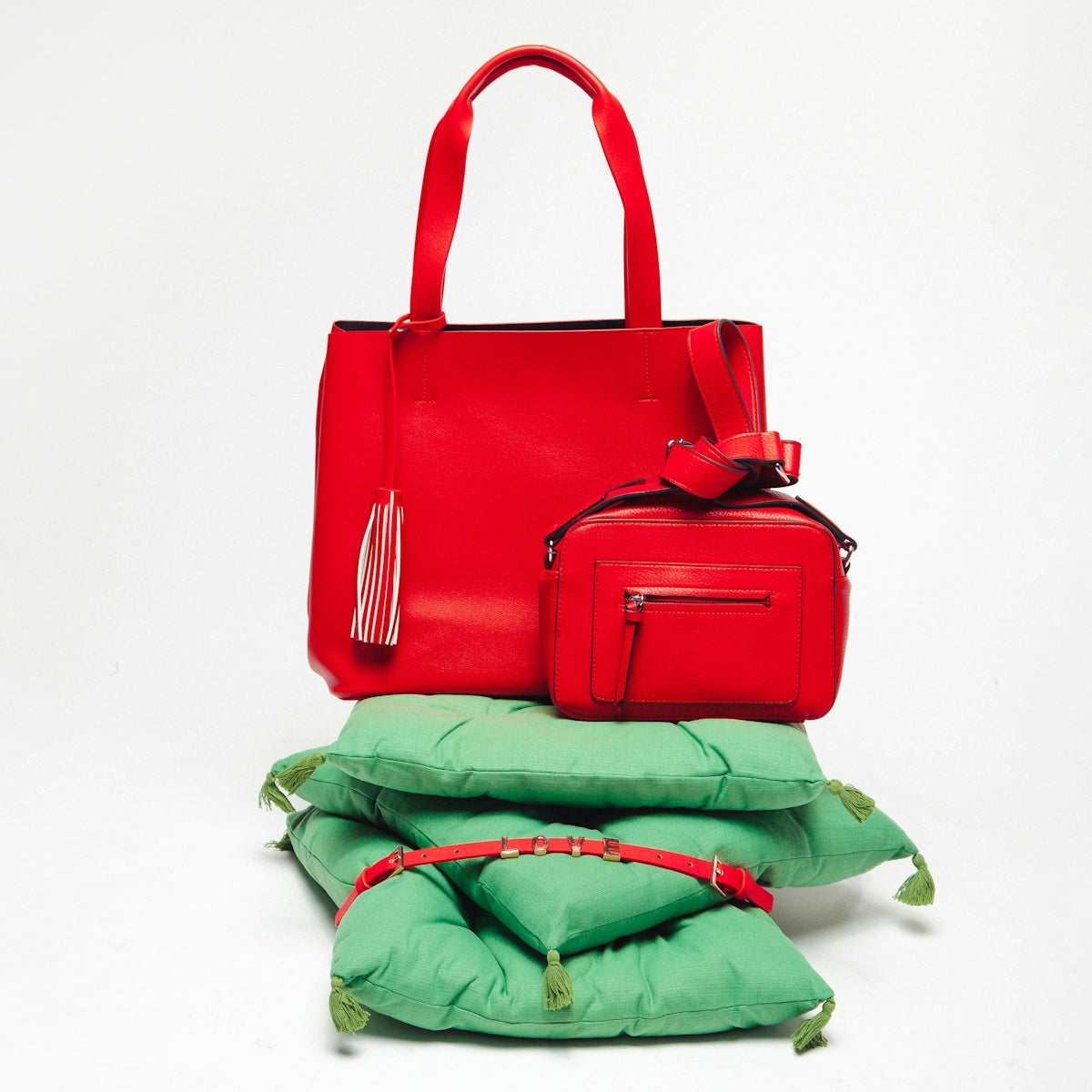 a red purse and a green pillow on a white background