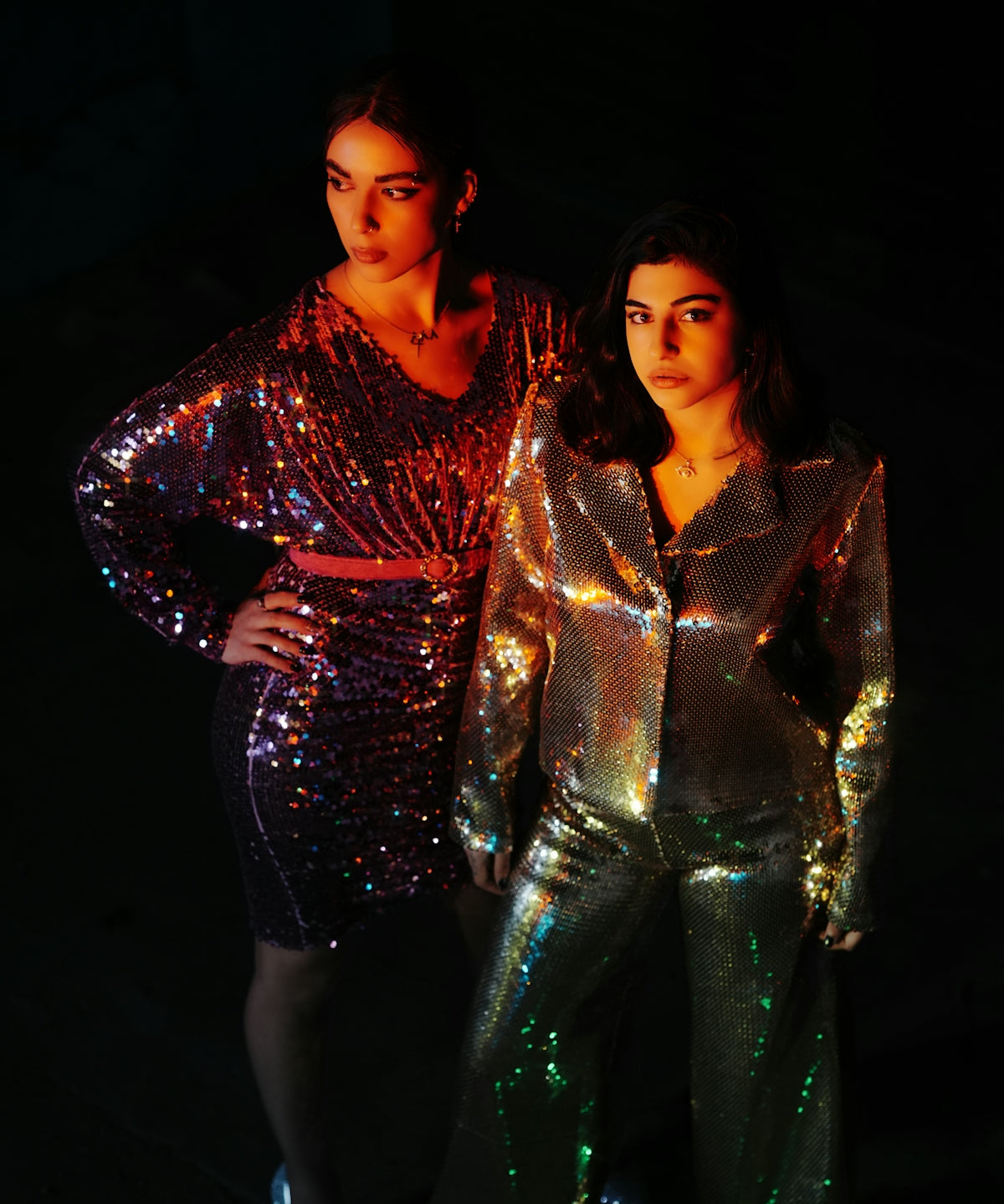 two women standing next to each other in shiny outfits