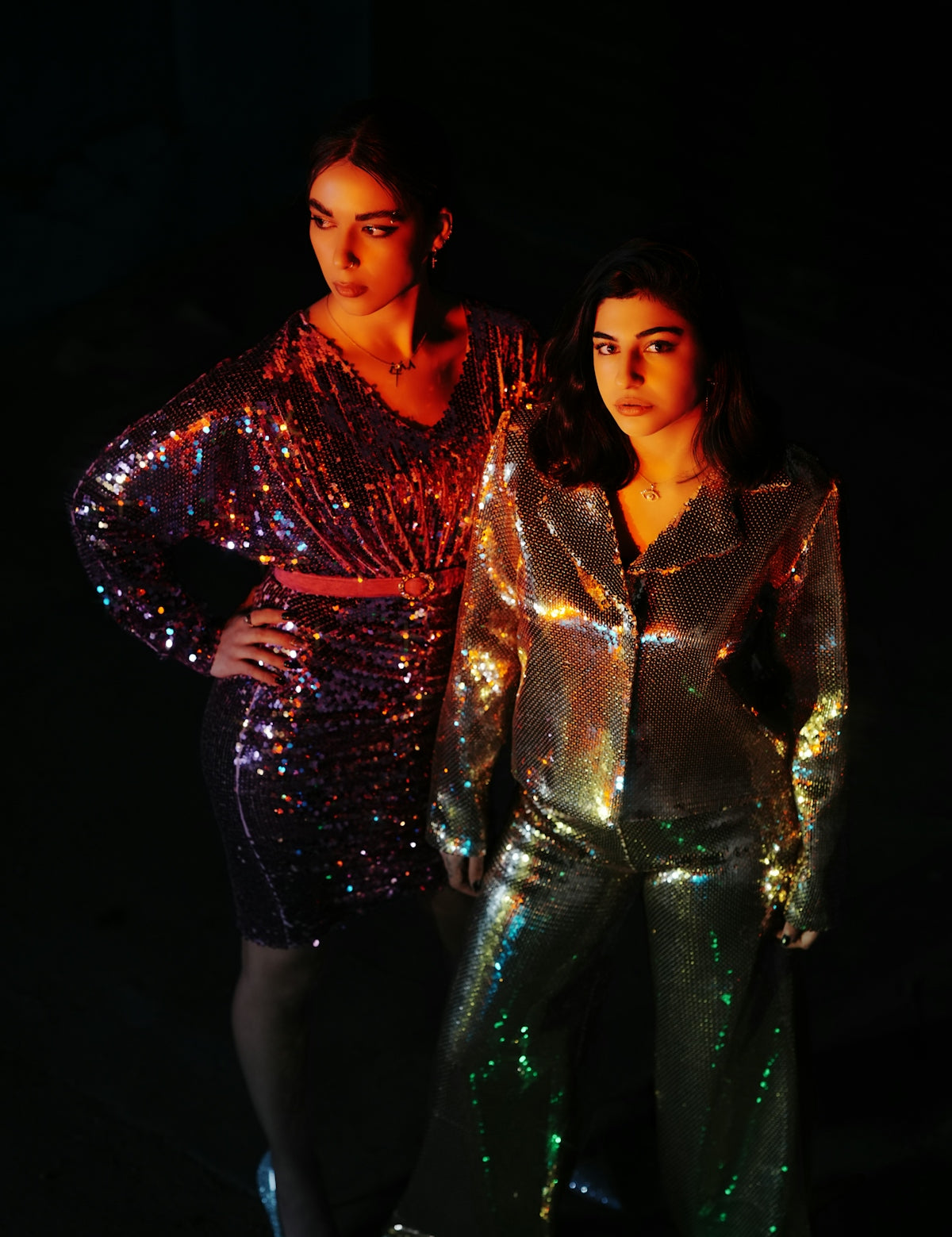two women standing next to each other in shiny outfits