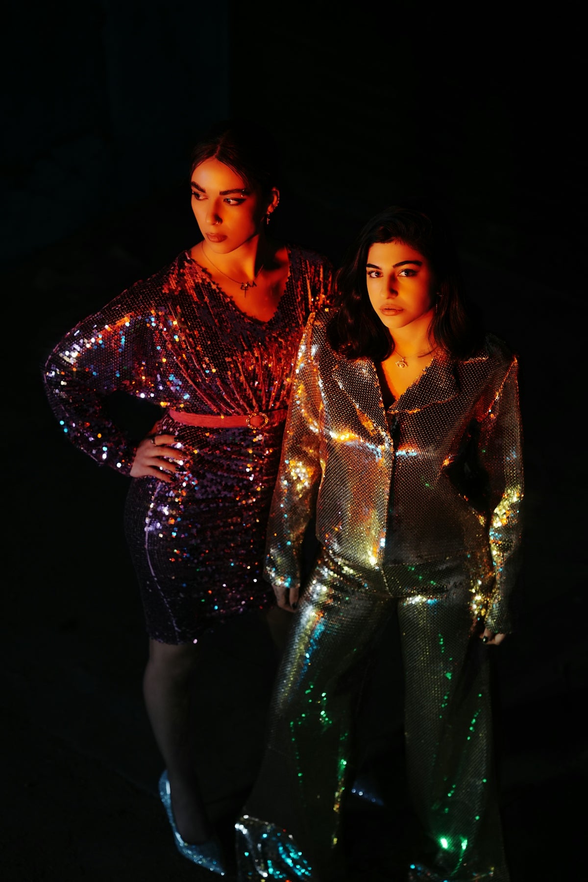 two women standing next to each other in shiny outfits