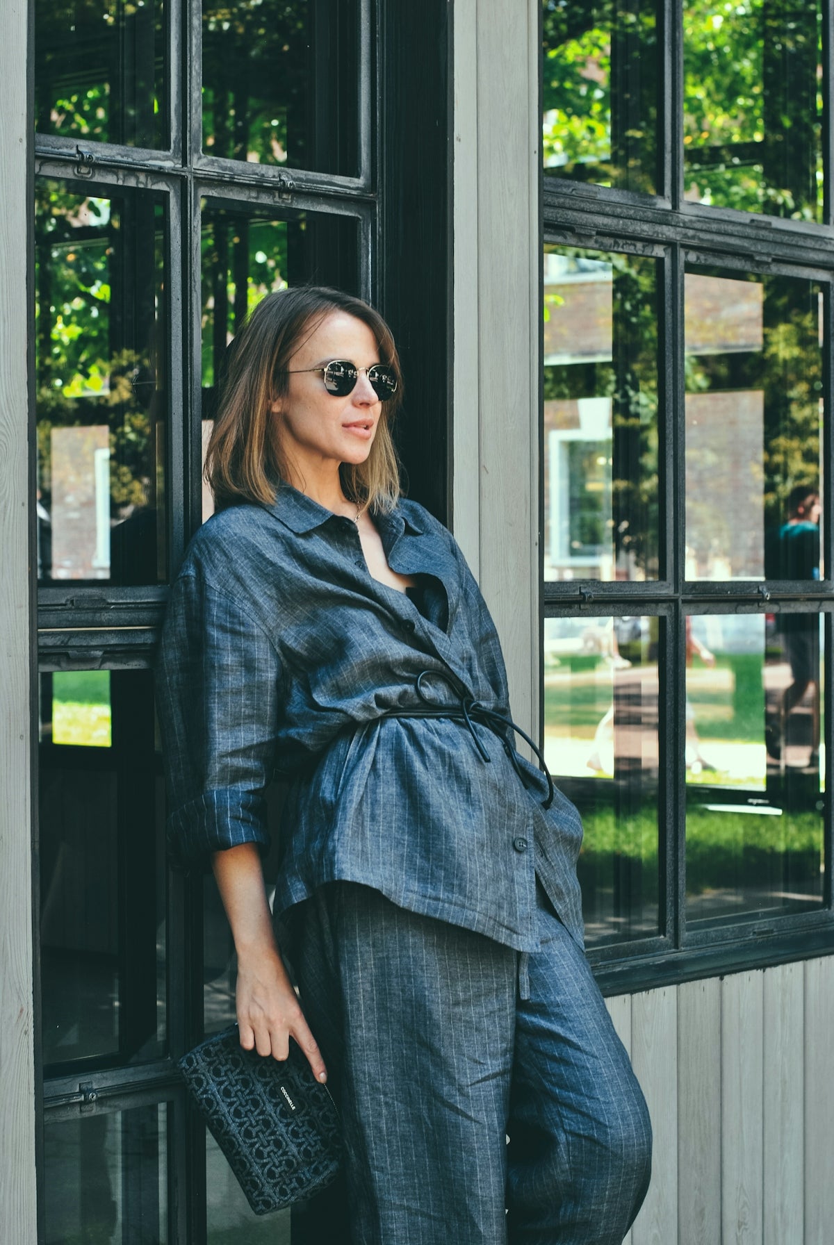 Woman in denim outfit poses by a window.