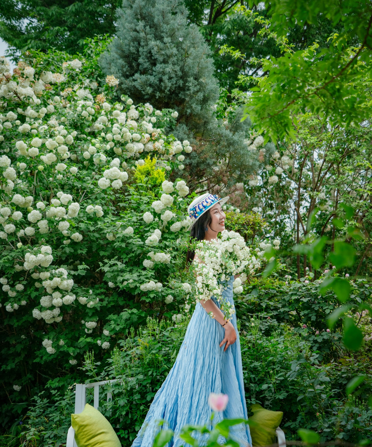 Woman in blue dress smiles in a beautiful garden.