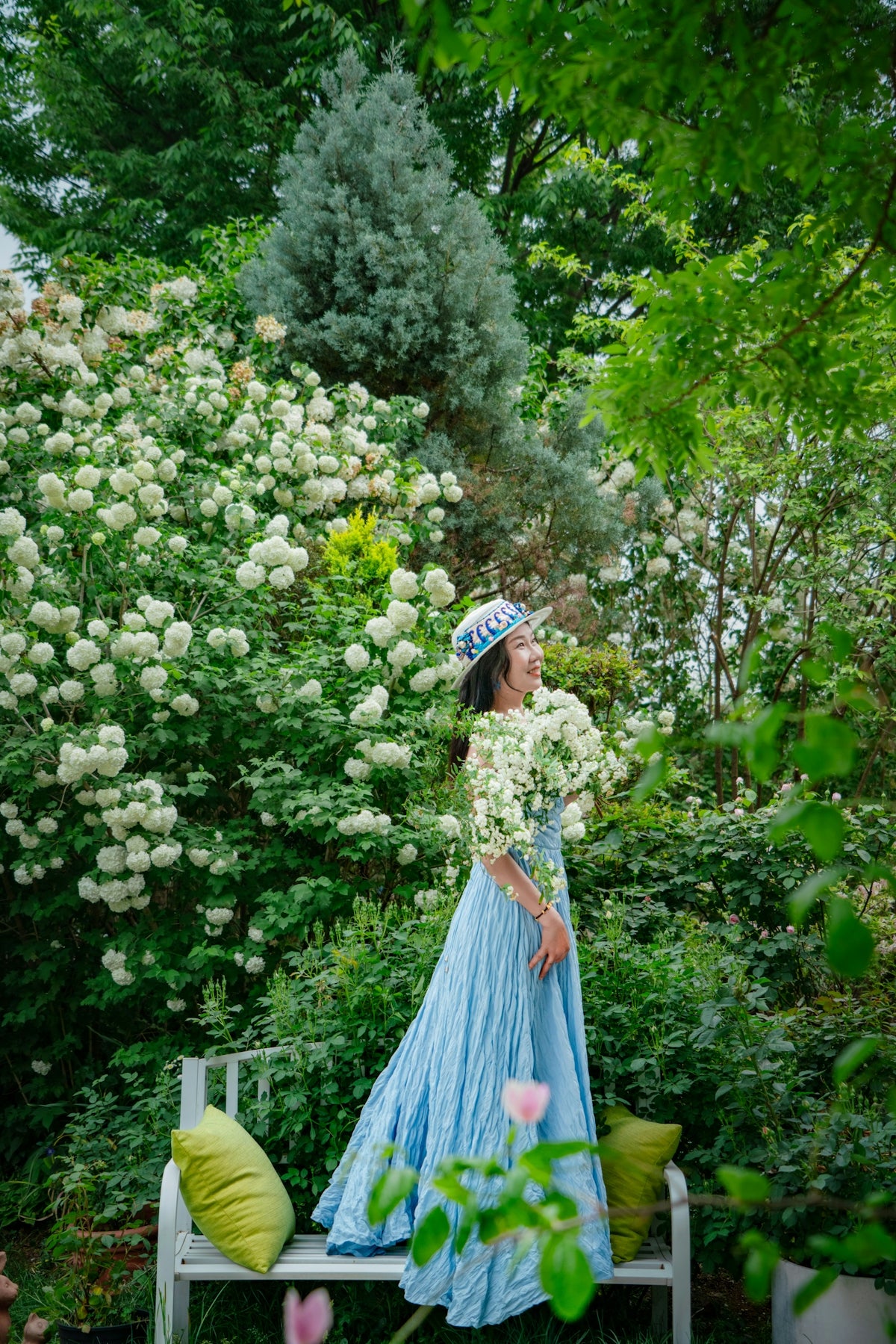 Woman in blue dress smiles in a beautiful garden.