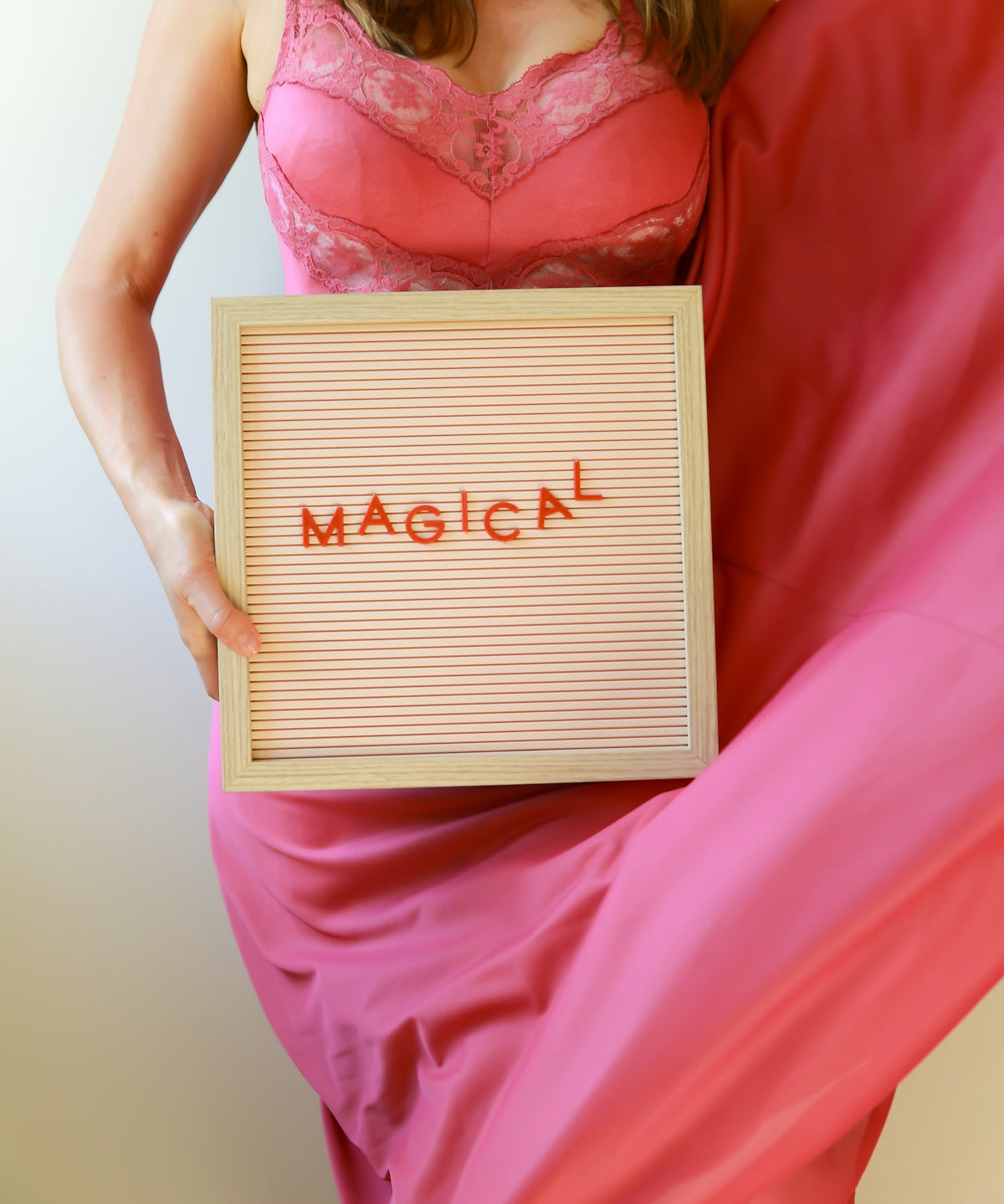 Woman in pink dress holds a sign saying magical.