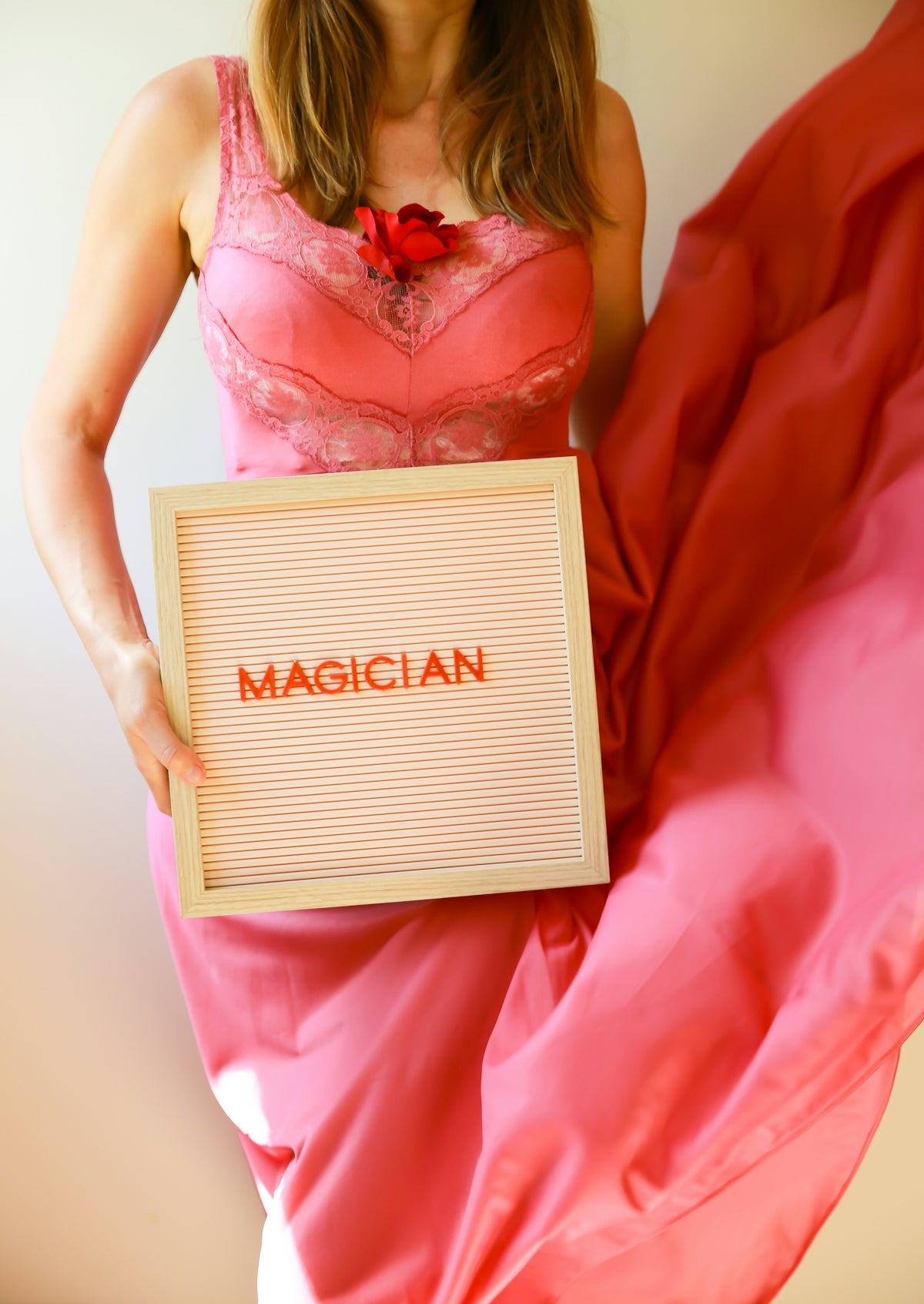 A woman poses, holding a sign that reads magician.