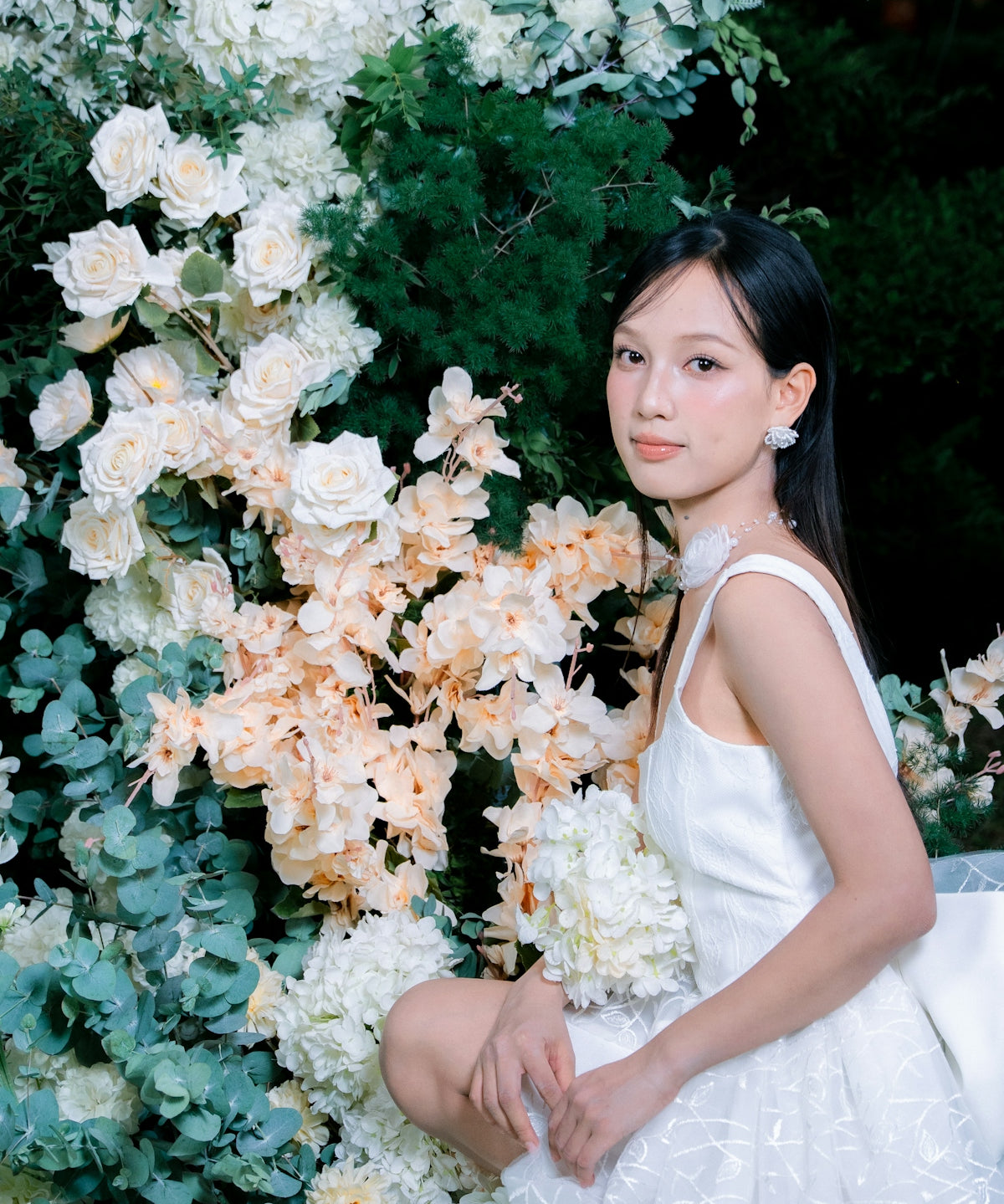 Woman in white dress posing with floral arrangement