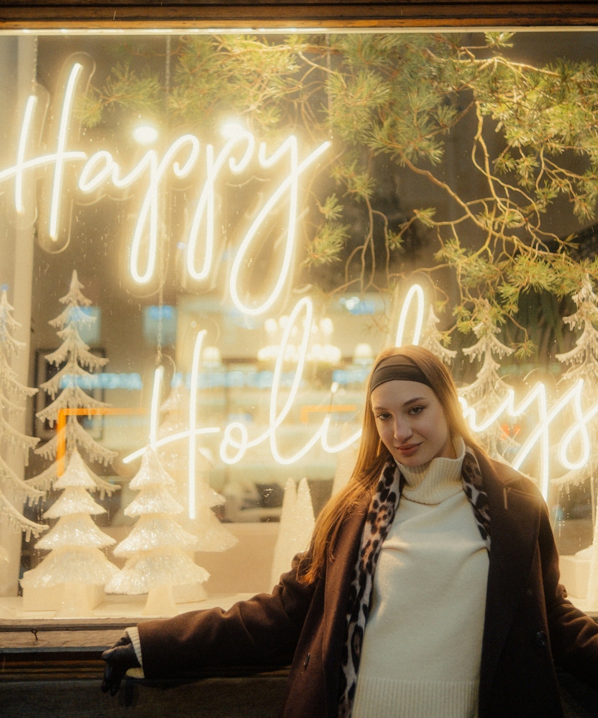 Woman in front of a happy holidays neon sign