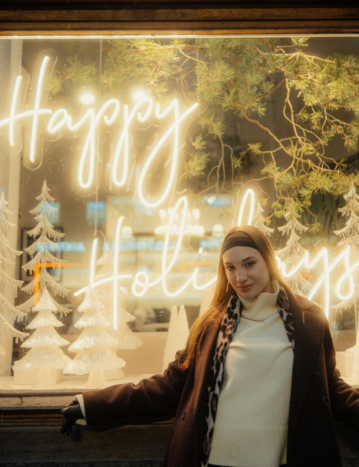 Woman in front of a happy holidays neon sign