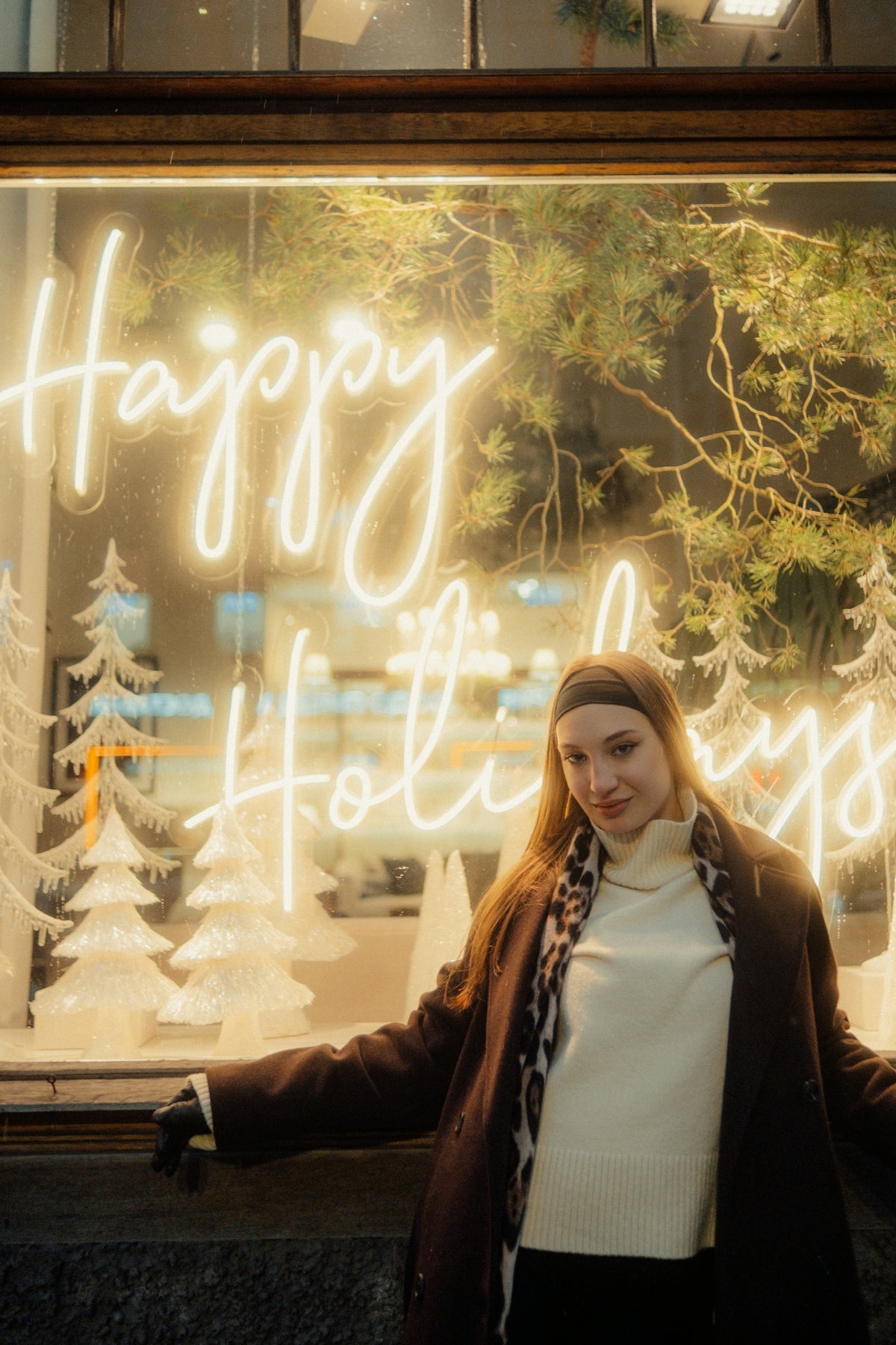 Woman in front of a happy holidays neon sign