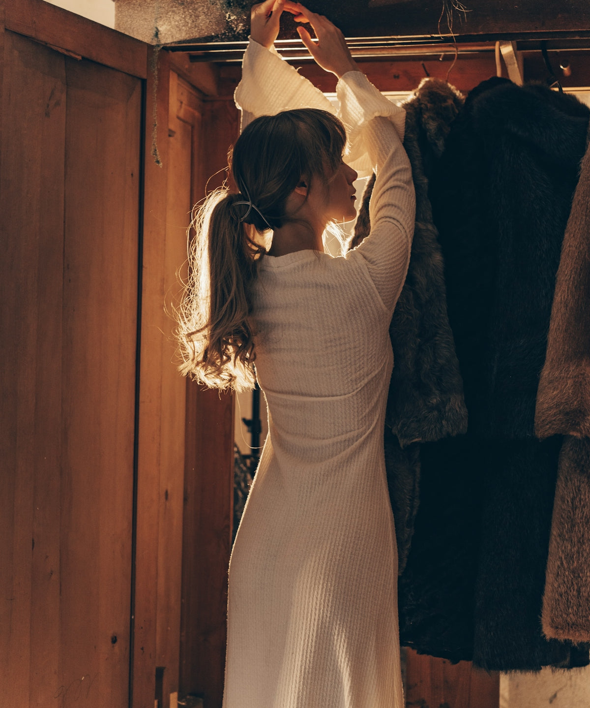 Woman selecting clothes from a wooden wardrobe.