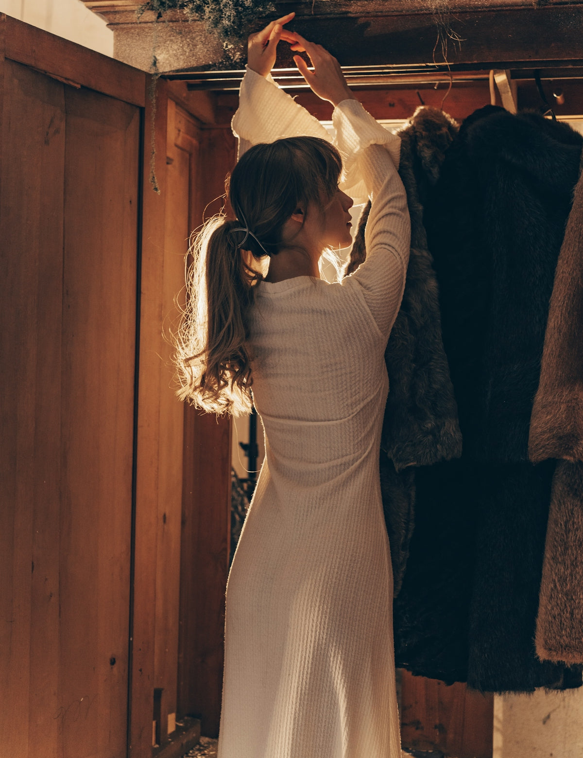 Woman selecting clothes from a wooden wardrobe.