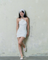 Woman wearing Éloise Garden Party Sequin Dress in white, sparkling mini dress perfect for summer. White dresses sparkly.