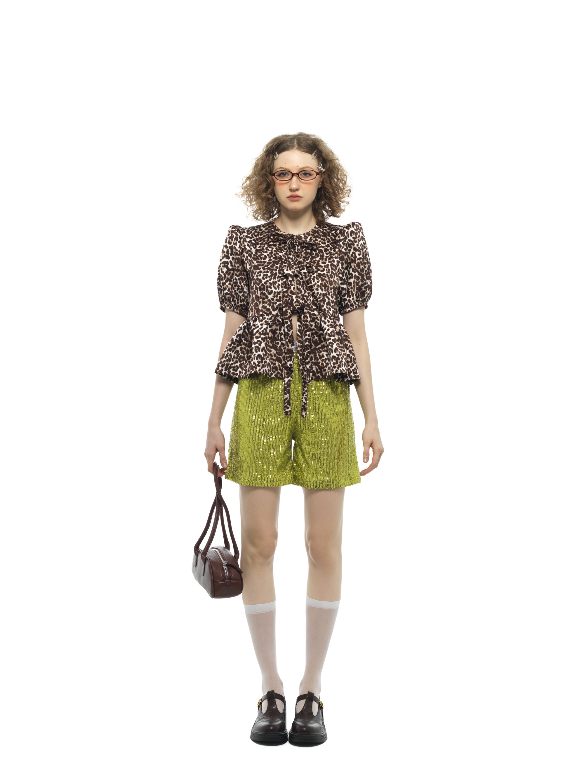 Model wearing green sequin shorts with a patterned top, styled for Nova Sequin Shorts product page.